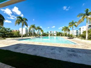 an empty swimming pool with palm trees and buildings at Your Crissere Tropical Dream RD in Punta Cana