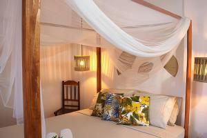 ein weißes Himmelbett mit Kissen im Schlafzimmer in der Unterkunft Casa charmosa em BG - Casa Trevo in Barra Grande