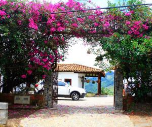 un coche aparcado en un estacionamiento con flores rosas en Casa Santamaria Hotel Campestre en Jericó