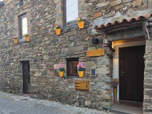 a stone building with potted plants on the side of it at Casa do Tear in Sobreira Formosa