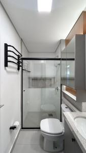 a bathroom with a toilet and a glass shower at Flat Planejado com Linda Vista e Escritório in Campo Grande