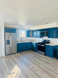 an empty kitchen with blue cabinets and a refrigerator at The Ostel in Los Angeles