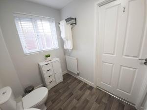 a white bathroom with a toilet and a window at Modern Flat with Comfort in Nottingham