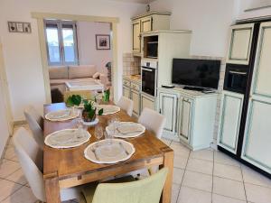 a dining room with a wooden table and a kitchen at Les Antilles, maison de bord de mer in Pirou