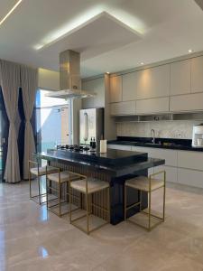 a kitchen with a large black counter and chairs at Casa com Piscina, área Gourmet e Ar Condicionado in Sumaré