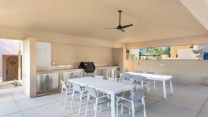 a dining room with white tables and chairs at Stunning 2BR Condo - 5 Min to Beach in Cabo San Lucas