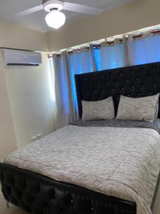 une chambre avec un grand lit avec une tête de lit noire dans l'établissement Brisa de mar BOCA CHICA,, à Boca Chica