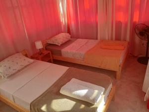 two beds in a small room with pink curtains at Maya Mindelo Studio T1 in Mindelo