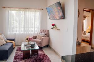 un salon avec un canapé, un fauteuil et une table dans l'établissement Cabañas con jacuzzi y chimenea - Casa Floral, Marinilla, à Marinilla