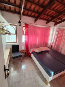 a bedroom with a bed with pink curtains and a chair at Maya Mindelo Studio T1 in Mindelo