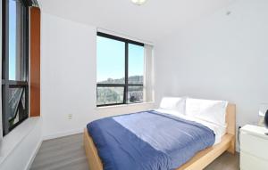 a white bedroom with a bed and a window at Entire Private Condo Unit, 1 parking space in Coquitlam