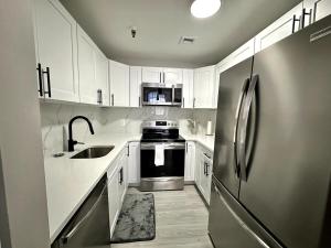 eine Küche mit weißen Schränken und einem Edelstahlkühlschrank in der Unterkunft Private Entrance Cozy Apt Bright Modern in Albany