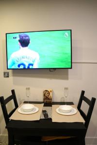 a tv on a wall above a table with two chairs at Central Cardiff One-Bed Comfortable Flat in Cardiff +9 photos