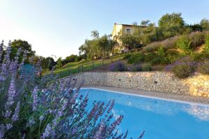 una piscina con una pared de piedra y flores púrpuras en Il Poggio Dell'Artilla, en Castiglione in Teverina