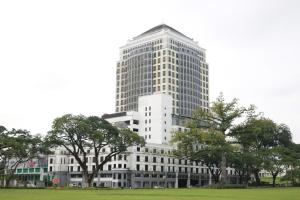 古晋梅德卡宫套房酒店的一栋高大的白色建筑，前面有树