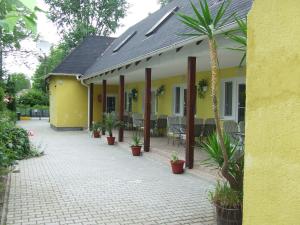 a yellow house with potted plants on a patio at Relax Apartmans in Balatonszemes