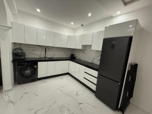 a kitchen with white cabinets and a black refrigerator at Nour DAsilah 8 in Asilah