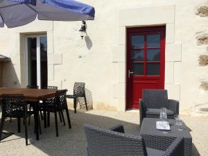 a patio with a table and chairs and a red door at Gîte rénové à Dommartin-le-Franc : confort, verdure et activités à proximité du lac du Der - FR-1-611-64 in Dommartin-le-Franc