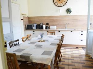 una cucina con tavolo, sedie e orologio sul muro di Manoir 19e 7 chambres, piscine chauffée, parc arboré proche lac en Champagne - FR-1-611-95 a Montier-en-Der