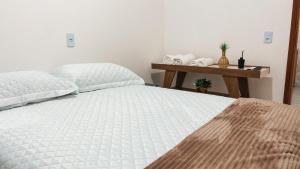 a bedroom with a white bed and a wooden table at Residencial Antônio Floriza in Sinop
