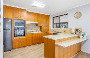 a kitchen with wooden cabinets and a stainless steel refrigerator at Bendigo Signature Accommodation on Garden Court in North Bendigo Junction