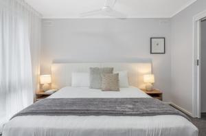 a white bedroom with a large bed with two lamps at Bendigo Signature Accommodation on Garden Court in North Bendigo Junction
