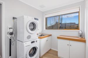 a laundry room with a washing machine and a window at Bendigo Signature Accommodation on Garden Court in North Bendigo Junction