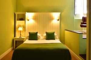 a bedroom with a large bed with two green pillows at Pousada Convento de Evora in Évora