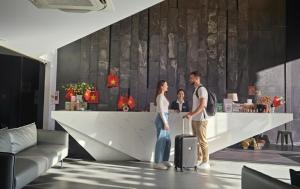 JBAY Beachfront Boutique Hotel في دا نانغ: رجل وامرأة يقفان عند المنضدة مع حقيبة سفر