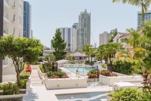 an apartment with a pool and trees and buildings at Trilogy Surfers Paradise in Gold Coast