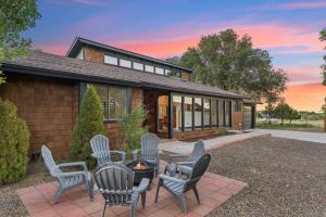 eine Terrasse mit Stühlen und einer Feuerstelle vor einem Haus in der Unterkunft Rare Modern Family Getaway ~ 3 Acres & Game Room in Elden Pueblo