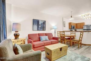 a living room with a red couch and a table at Ski-In Ski-Out Zephyr 1 Bedroom Condo 2204 in Winter Park