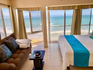 a bedroom with a bed and a couch in front of the ocean at Suites Atlas - Ocean Front in Bucerías +178 photos