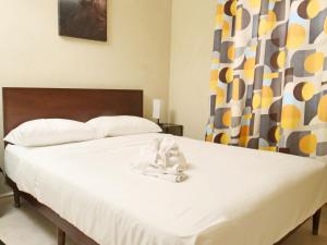a white bed with a stuffed animal sitting on it at Casa Amarilla St Michael in Bridgetown