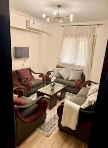 a living room with couches and a table at Stylish Apt in Jannah Compound Al Sheikh Zayed in Sheikh Zayed
