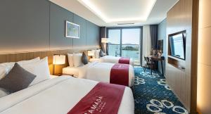 a hotel room with two beds and a window at Ramada Plaza by Wyndham Dolsan Yeosu in Yeosu +37 photos