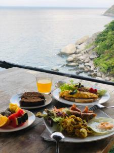 a table with plates of food and a view of the water at Kohtao Hillside resort in Koh Tao