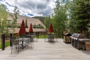 eine Terrasse mit Tischen und Stühlen mit Sonnenschirmen und einem Grill in der Unterkunft Pines 2158 by Summit County Mountain Retreats in Keystone
