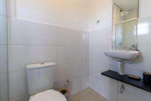 a white bathroom with a toilet and a sink at ApTropea: Conforto, Natureza e o Som do Mar in Praia Guaratuba