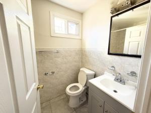 a bathroom with a toilet and a sink and a mirror at Luxury 3BR 2BA Retreat NYC Getaway Free Parking in Jersey City +27 photos