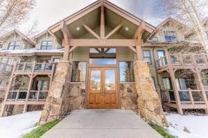 Una casa con una puerta de entrada de madera en la nieve. en Highland Greens Lodge 311 by Summit County Mountain Retreats, en Gold Hill