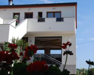 a white house with red flowers in front of it at Rooms Edda in Umag
