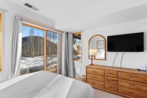 a bedroom with a bed and a tv and a window at Quicksilver 1621 by Summit County Mountain Retreats in Keystone