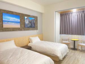 a hotel room with two beds and a window at 看海季節&聽海約定精緻旅店 in Magong