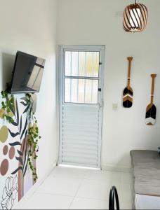 - un salon avec une porte, une télévision et un canapé dans l'établissement Casa Beira Mar - Vista do Mar pela Janela da Sala, perfeita, em frente à praia da enseada Sesc Bertioga, à Bertioga