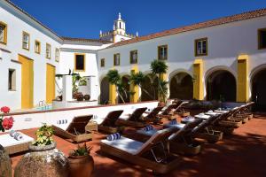 a courtyard with lounge chairs and a building at Pousada Convento de Evora in Évora