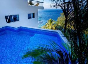 a swimming pool in front of a house and the ocean at Oceanfront 4BR 20 PAX in Puerto Vallarta