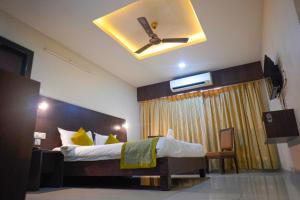 a bedroom with a bed with a ceiling fan at Hotel Green Park Elite in Kākināda