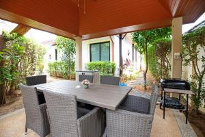 ein Holztisch und Stühle auf einer Terrasse in der Unterkunft Orchid Villa - 3 Bedrooms Pool Villa - Rawai beach in Rawai Beach
