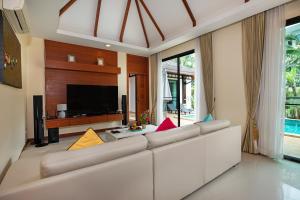 ein Wohnzimmer mit einem weißen Sofa und einem Fernseher in der Unterkunft Orchid Villa - 3 Bedrooms Pool Villa - Rawai beach in Rawai Beach